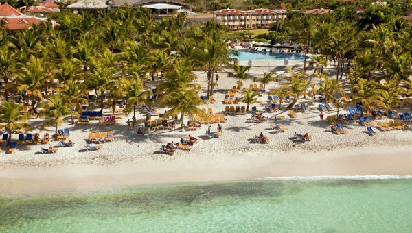 Wunderbarer Sandstrand mit vielen Palmen, Pool und Hotel im Hintergrund